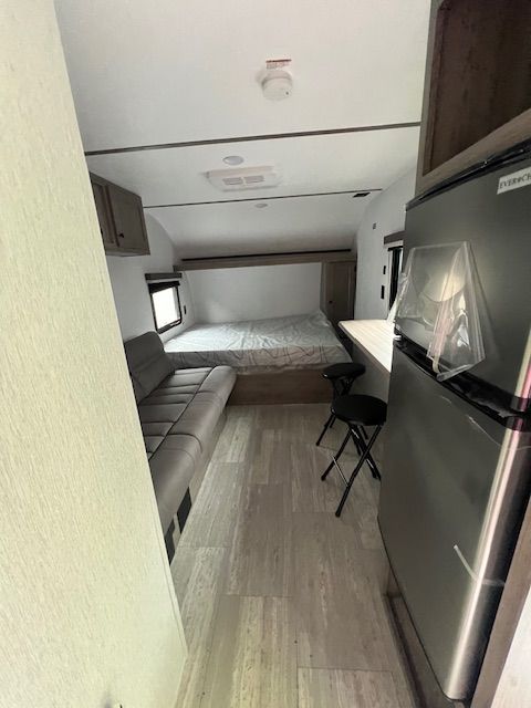A rv with a refrigerator , couch , chairs and a bed.