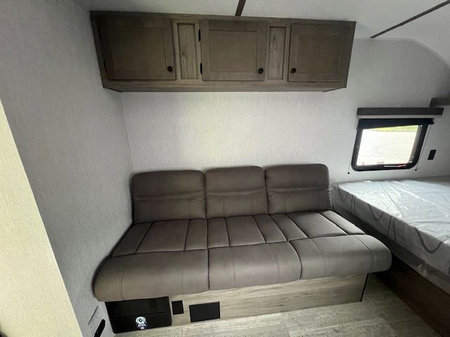 There is a couch in the middle of the room next to a bed.