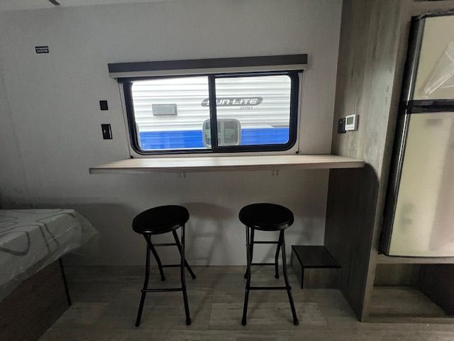 A rv with a table and two stools in front of a window.