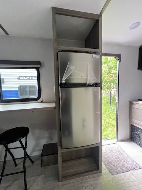 There is a stainless steel refrigerator in the middle of the room.