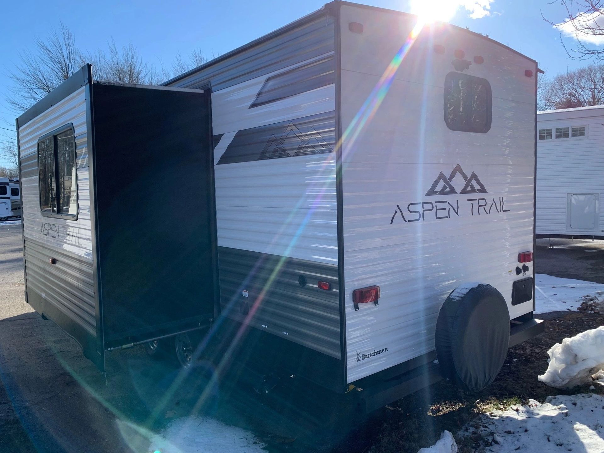 A white and black trailer is parked in the snow.