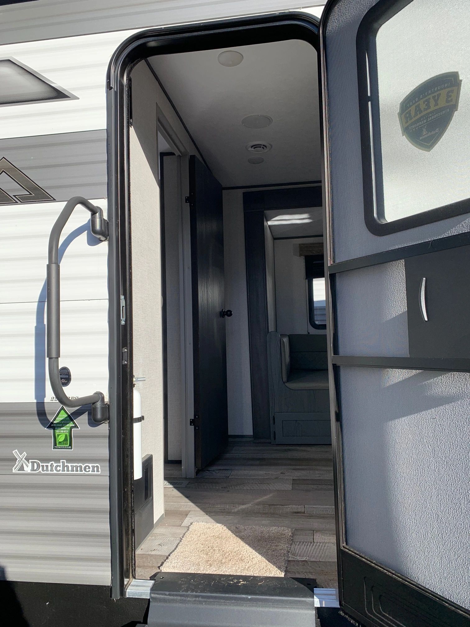 The door of a trailer is open and leading to a hallway.