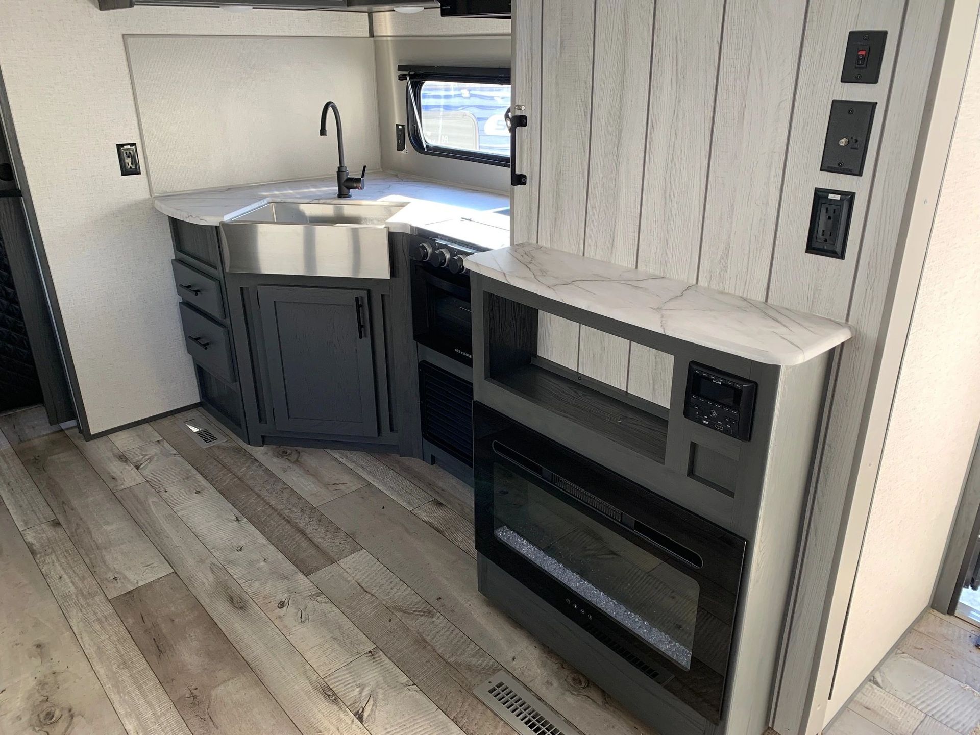 A kitchen in a rv with a sink , stove , and fireplace.