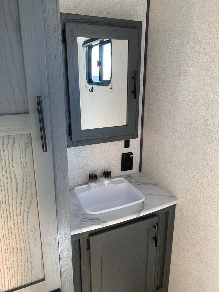 A bathroom with a sink , mirror and cabinet.