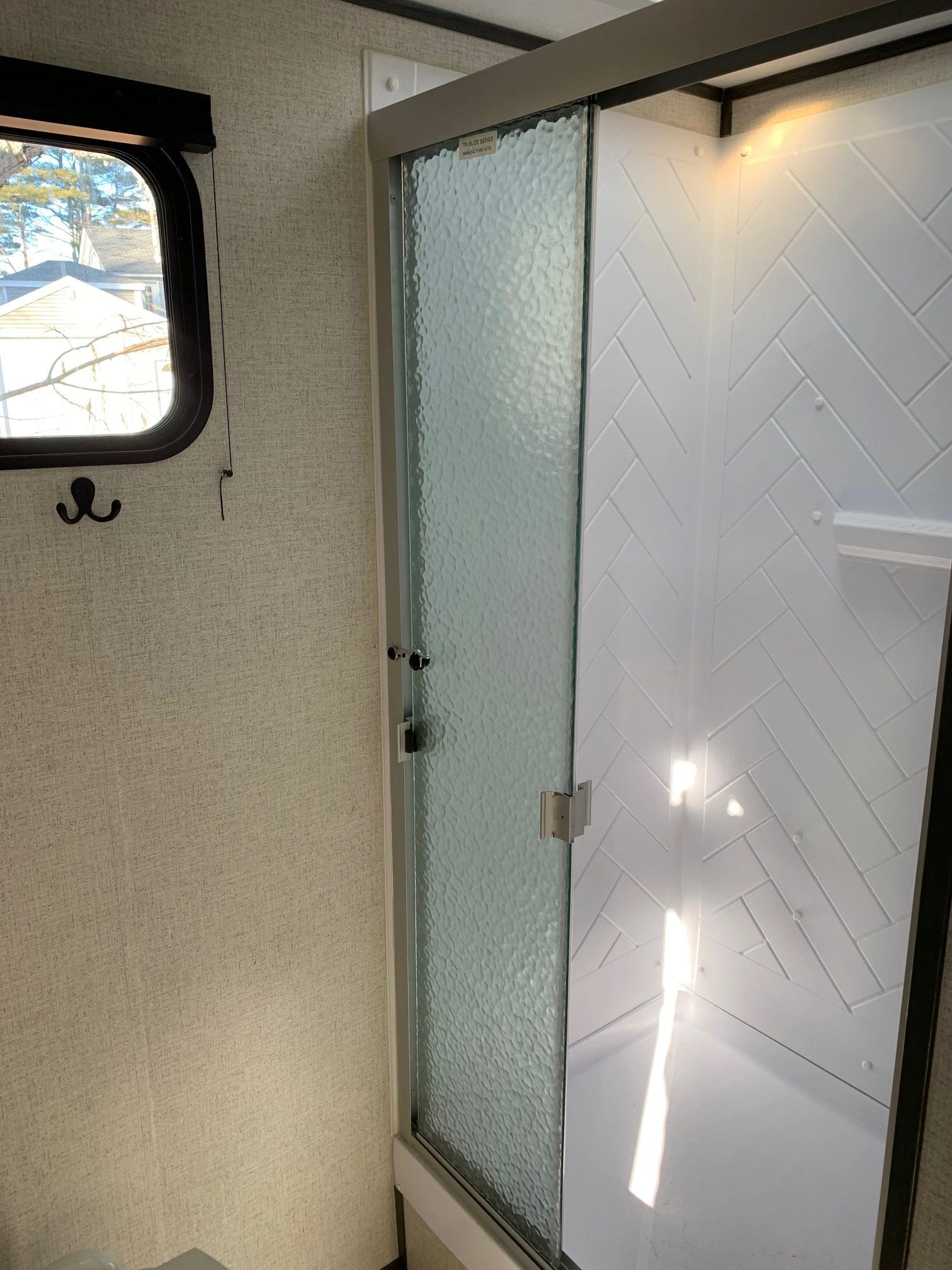A bathroom with a sliding glass shower door and a window.