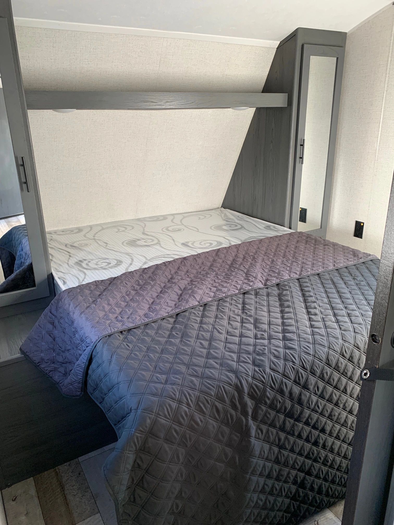 A bedroom in a trailer with a bed and bunk beds.