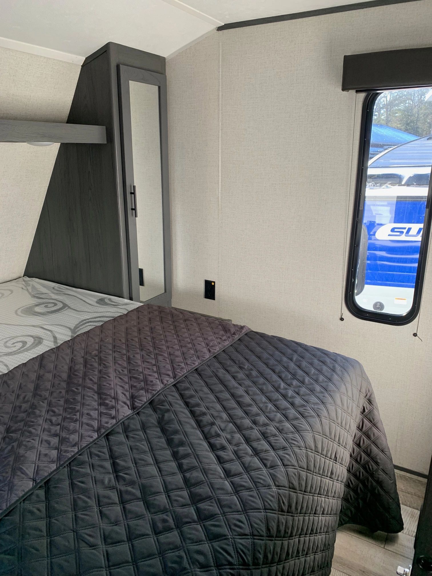 A bedroom in a trailer with a bed and a window.