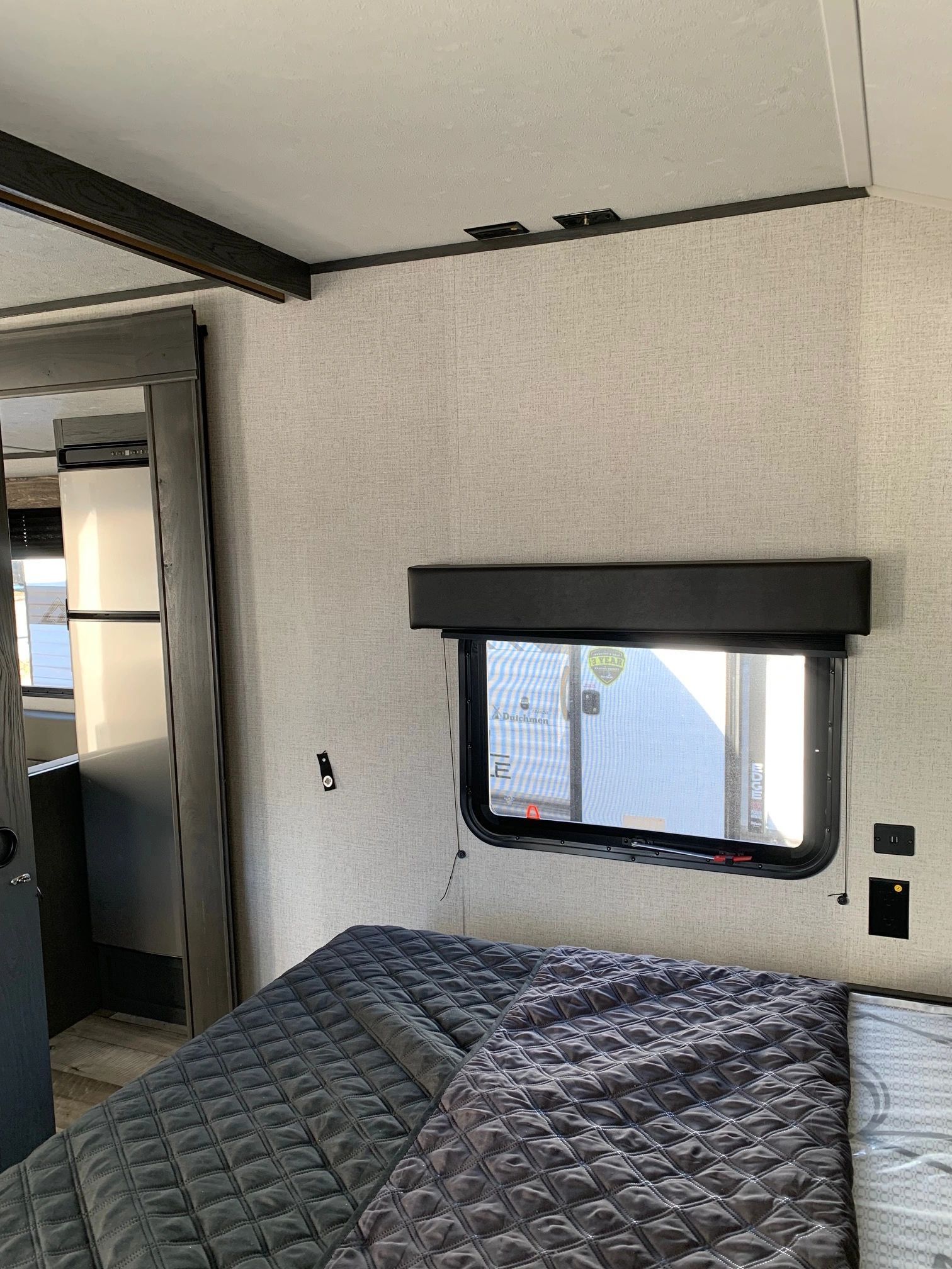 A bedroom in a trailer with a bed and a window.