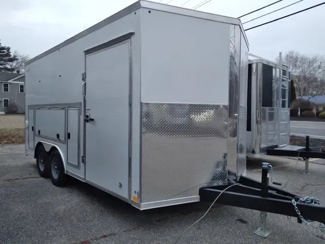A white trailer is parked on the side of the road.