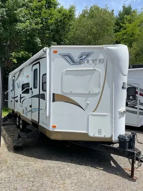 A white rv is parked in a gravel lot.