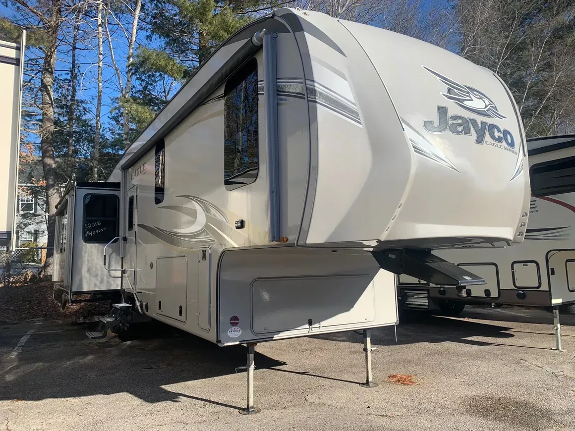 A white jayco rv is parked in a gravel lot.