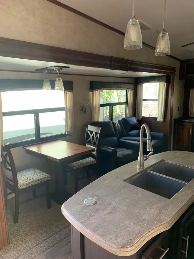 A kitchen with a sink , table , chairs and a couch.