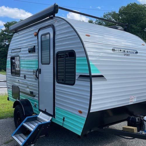 A small camper trailer is parked on the side of the road.
