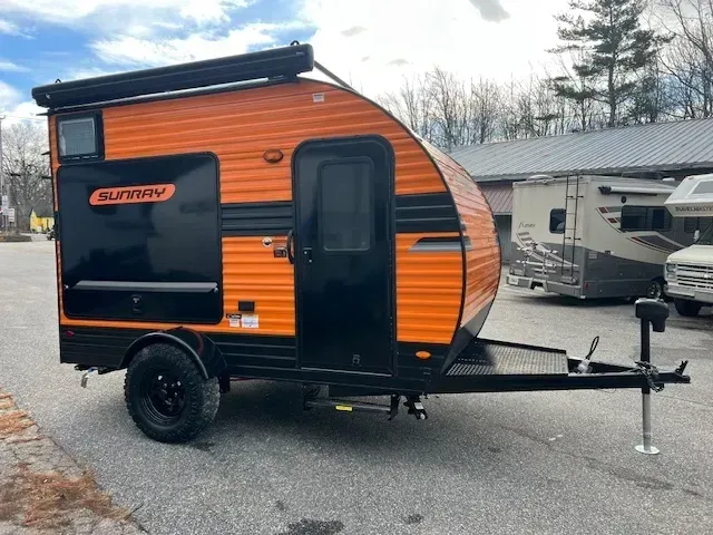 A small orange and black trailer is parked in a parking lot.