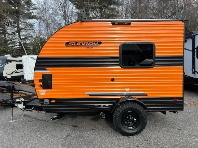A small orange and black trailer is parked in a parking lot.