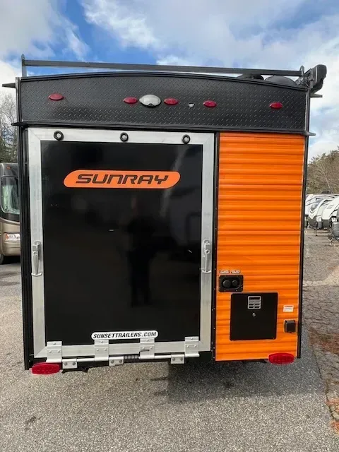 A black and orange trailer is parked in a parking lot.