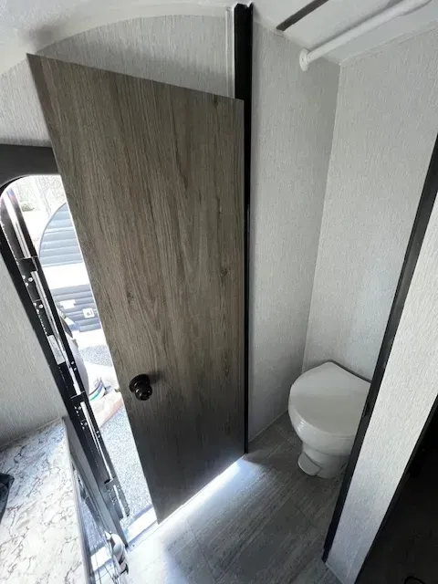 A bathroom with a toilet and a door open.