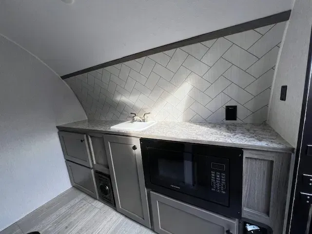 A kitchen with a sink , microwave , and cabinets.