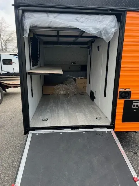 The inside of a trailer with the door open and a ramp.