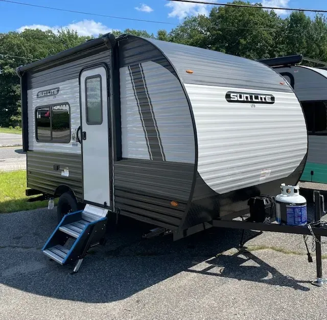 A small camper trailer is parked on the side of the road.