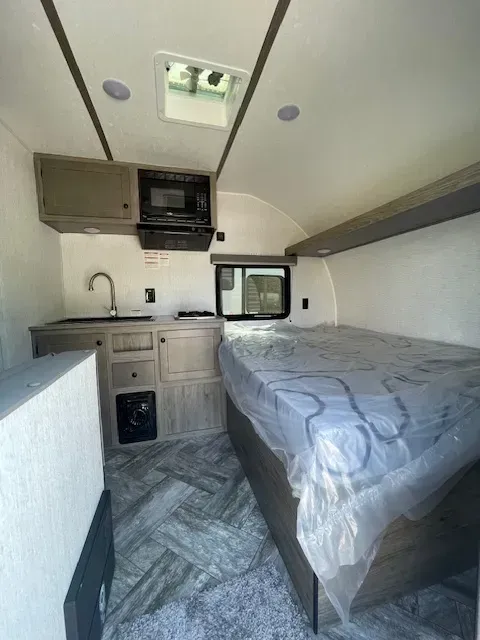 The inside of a camper with a bed and a kitchen.