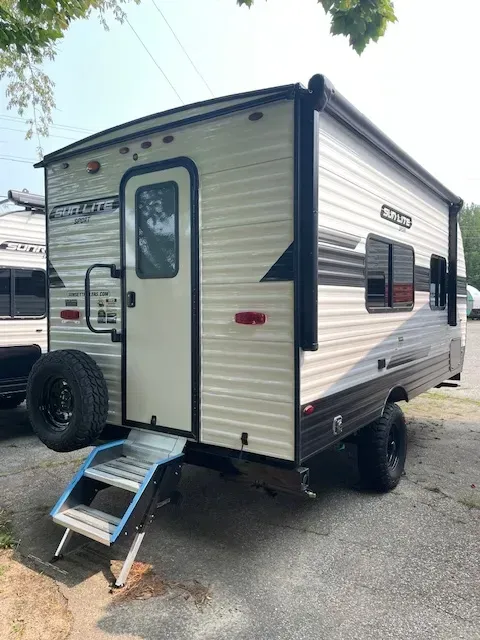 A small trailer with stairs attached to it is parked in a parking lot.