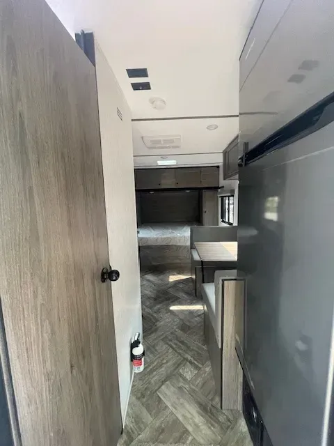 A hallway in a camper with a door open and a fire extinguisher.