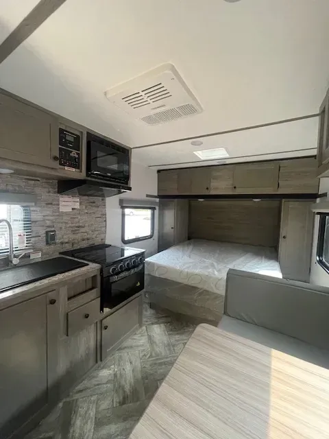 The inside of a rv with a bed and a kitchen.
