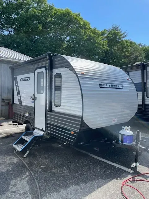 A small trailer is parked in a parking lot next to a building.