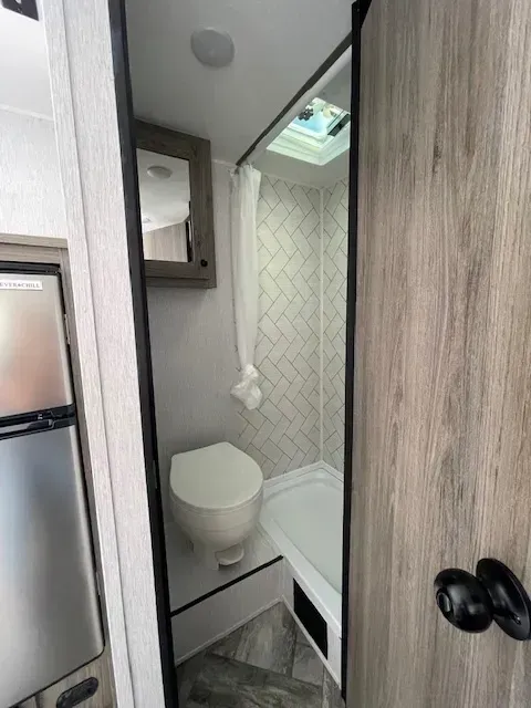 A bathroom in a rv with a toilet and shower.