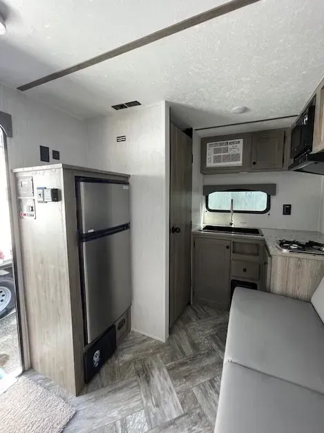 The inside of a rv with a couch and a refrigerator.