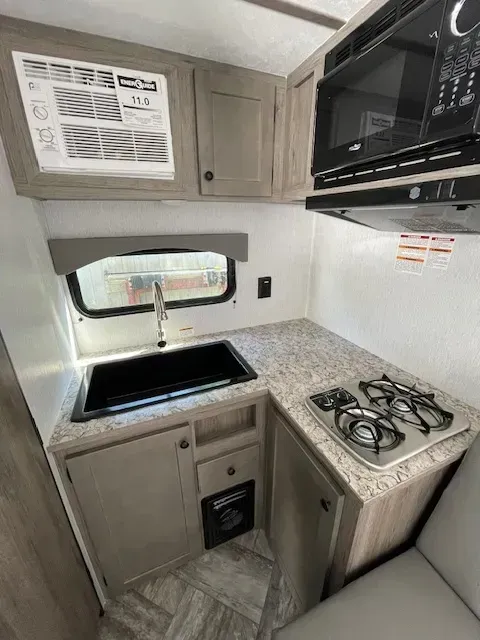 A kitchen in a trailer with a sink , stove , and microwave.