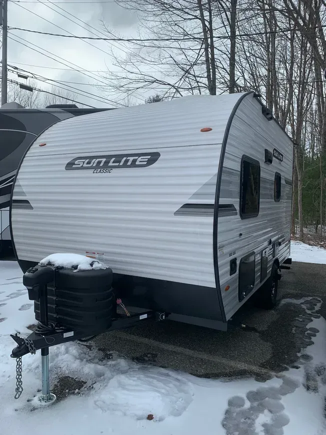 A white trailer is parked in the snow in a parking lot.