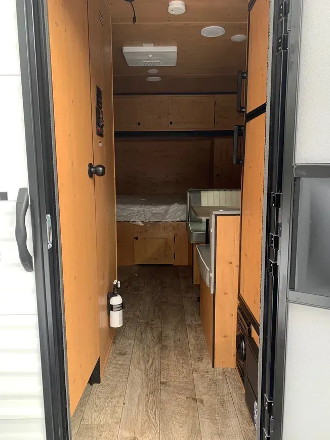 The inside of a trailer with a bed and a fire extinguisher.