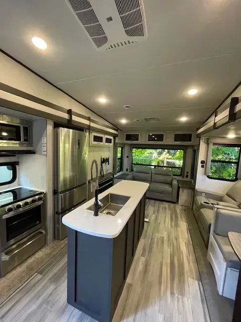 The inside of a rv with a kitchen and living room.