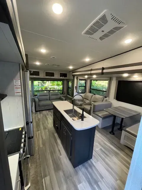 The inside of a rv with a kitchen , living room , and dining area.