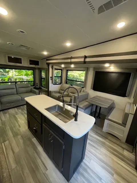 A kitchen in a rv with a sink and a couch.