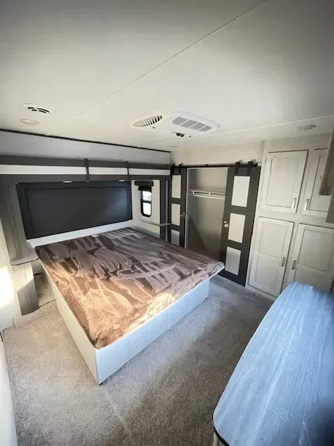 A bedroom in a camper with a large bed and lots of cabinets.