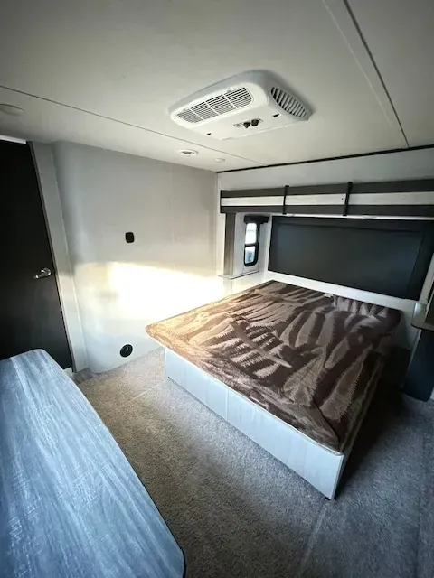 A bedroom in a trailer with a bed and a ceiling fan.