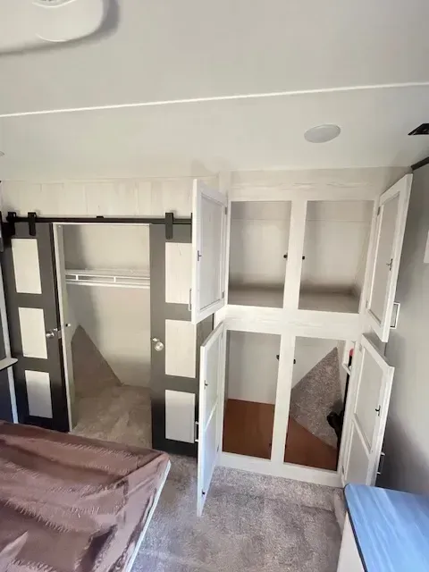A bedroom with a bed and a closet with the doors open