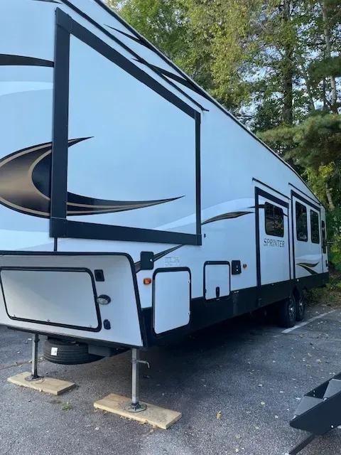A white and black rv is parked in a parking lot