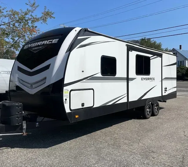 A white and black trailer is parked in a parking lot.