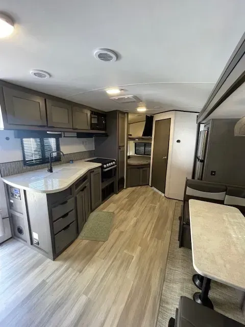 A kitchen in a rv with a table and chairs.