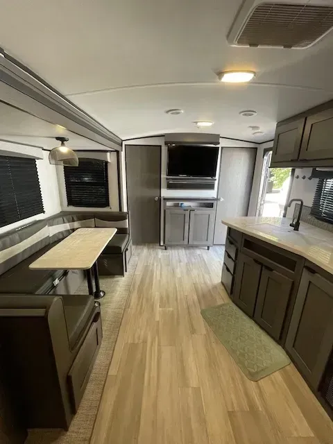 The inside of a rv with a table and a television.