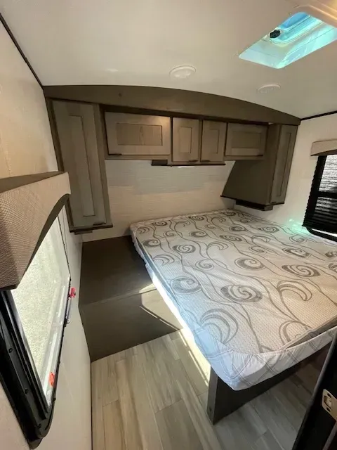 A bedroom in a camper with a bed and a skylight.