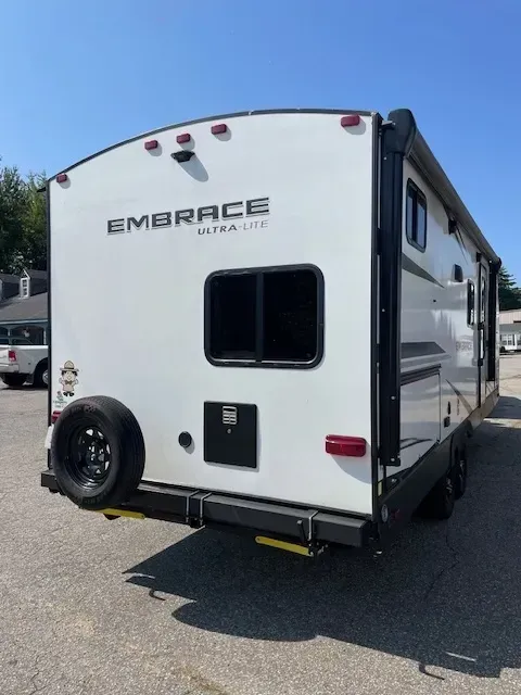 A white rv with the word embrace on the back