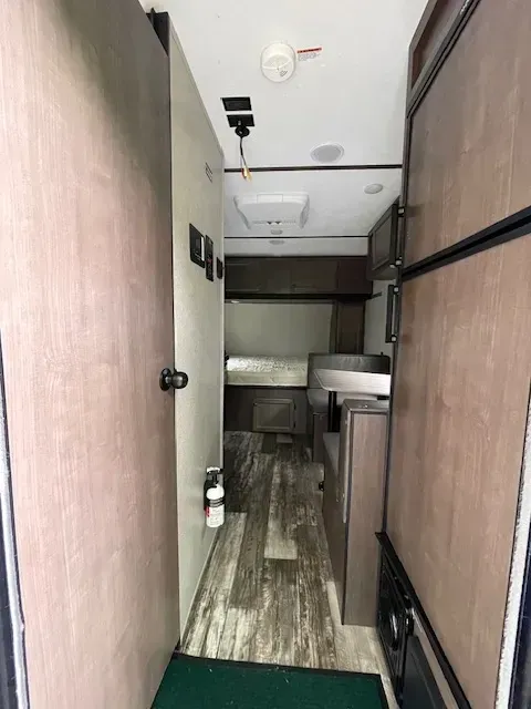 A hallway in a trailer with a green mat on the floor.