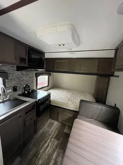 A rv with a bed , couch , and kitchen.