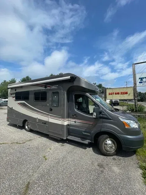 A rv is parked in a parking lot next to a building.