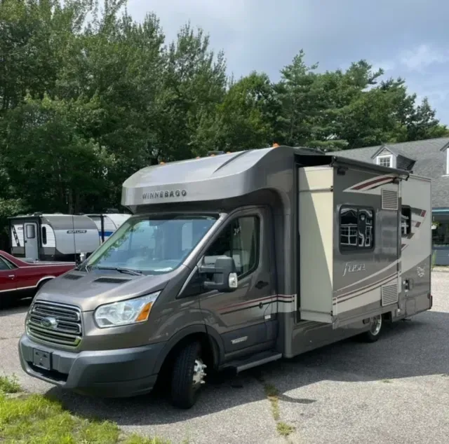 A rv parked in a parking lot with the door open